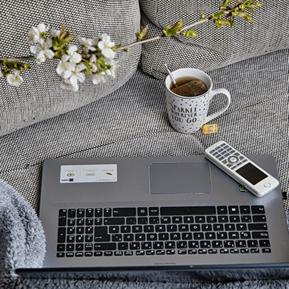 Laptop mit Telefon und Kaffee auf der Couch